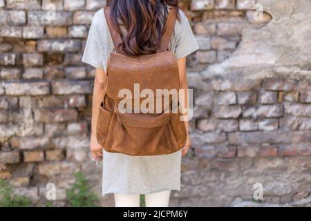Back of woman with brown leather backpack. Unisex bag for sale. Unbranded backpack. Stock Photo