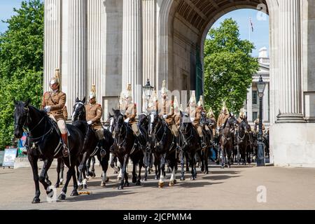 Queens Life Guards riding horses through Wellington Arch, Hyde Park Corner, London, England, United Kingdom on Wednesday, May 18, 2022. Stock Photo