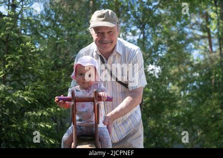 Grandfather father swinging baby at a playground Stock Photo