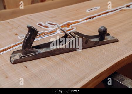Old metallic jointer plane laying on wood table. Woodworking tools on wooden table. Carpentry workshop Stock Photo