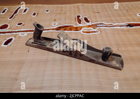 Old metallic jointer plane laying on wood table. Woodworking tools on wooden table. Carpentry workshop Stock Photo