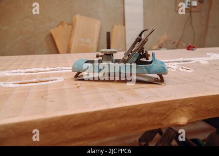 Old metallic jointer plane laying on wood table. Woodworking tools on wooden table. Carpentry workshop Stock Photo