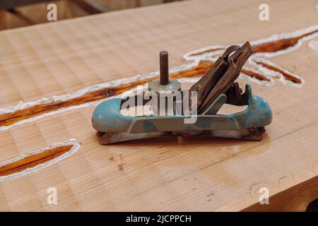 Old metallic jointer plane laying on wood table. Woodworking tools on wooden table. Carpentry workshop Stock Photo