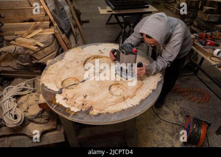 Man working with wood router on a wooden table in workshop Stock Photo