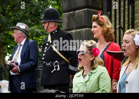Haworth 1940 event - (performers performing live, men in retro police officer's & photographer's costumes) - Main Street, West Yorkshire England UK. Stock Photo