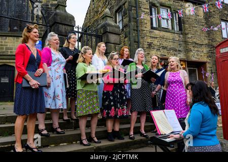 Haworth 1940 retro living history event (ladies' choir performing music, keyboard player, Union Jack bunting) - Main Street, West Yorkshire England UK Stock Photo