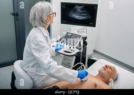 Heart ultrasound exam for senior man with ultrasound specialist while medical exam at hospital Stock Photo