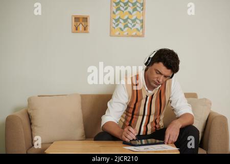 Pensive architect working from home, listening to music and making corrections in apartment floor plan Stock Photo