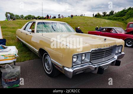 Three-quarters front view of a Gold, 1972, Chrysler New Yorker four-door hardtop, on display at the Deal Classic Car Show 2022 Stock Photo