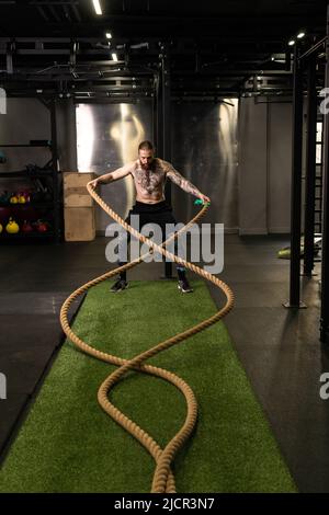 Rope training man warehouse fitness gym muscular exercising exercise workout, concept strong heavy from body from sportsman sport, muscle wave Stock Photo