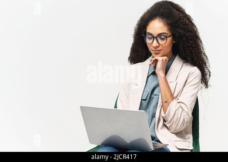 Smart and confident African-American woman in smart wear using laptop isolated on white background, female office employee or student typing, web browsing Stock Photo
