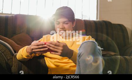 Man watching education and business videos on his cell phone sitting in his living room. Young man watching entertainment videos. Cheerful person watc Stock Photo