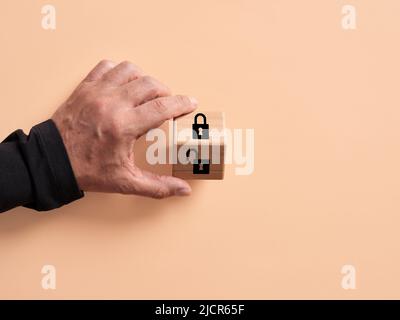Hand turns the wooden cube with open and closed padlock symbols. Internet security and code hacking concept. Stock Photo