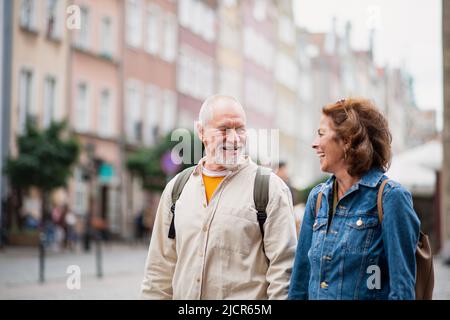 Portrait of happy senior couple tourists using smartphone outdoors in historic town Stock Photo