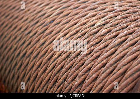 Steel cable sling hoist. Old obsolete rusty steel braided cable wounded on drum of industrial winch macro closeup texture background. Stock Photo