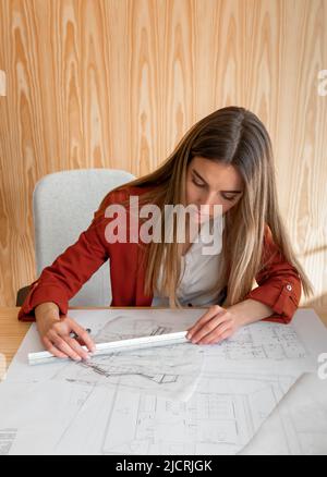 Young and beautiful woman working in architectural project with wood wall behind Stock Photo