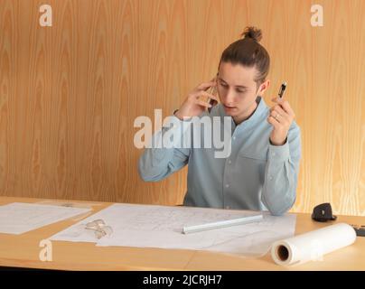 Young bussinesman talking over the smartphone with clients at office space with wooden background Stock Photo