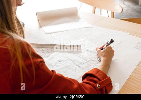 Young woman designer drawing on blueprints and sketches at office Stock Photo