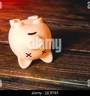 Lying dead piggy bank. High debt and depleted savings. Empty budget. Bankruptcy and business closure. High inflation. Depletion of financial reserves. Stock Photo