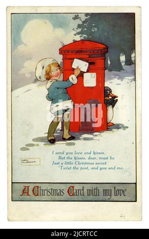 Original WW1 era, charming Christmas postcard illustrated by Agnes Richardson, girl in Victorian or Edwardian style clothes posting a Christmas card in a red pillar box, a cheeky penguin peers around the post box, posted and dated 23 December 1916. Stock Photo