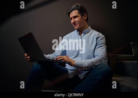 Successful Caucasian businessman, entrepreneur, sales manager, interior designer, freelancer works on laptop, plans new project, develops business str Stock Photo