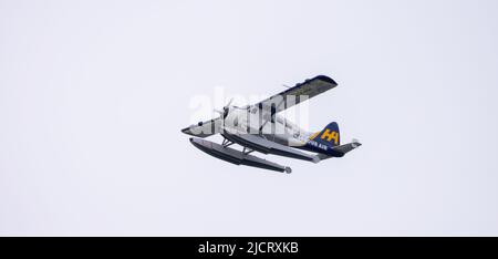 Harbour Air Seaplane leaving Coal Harbour. Cloudy Sky Background. Stock Photo