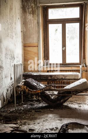 July 2022, Italy, Urbex. Dilapidated room with medical bed in an abandoned college Stock Photo