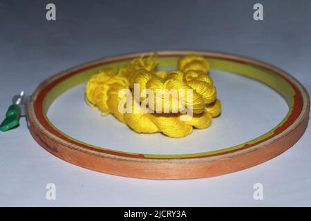 yellow colored wool yarn bunch with hand wood circle frame for embroidery Stock Photo