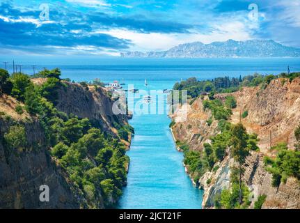 Beautiful landscape of the Corinth Canal in a bright sunny day against a blue sky with dramatic clouds. A pleasure boat floats among the rocks.Greece Stock Photo
