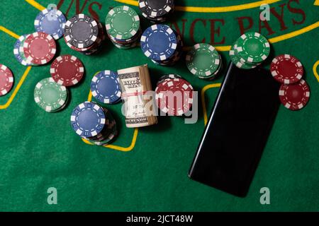 Cards, phone, casino chips and dice close up. Computer keyboard and smartphone, illuminated with pink light. Concept of gambling, online betting in Stock Photo