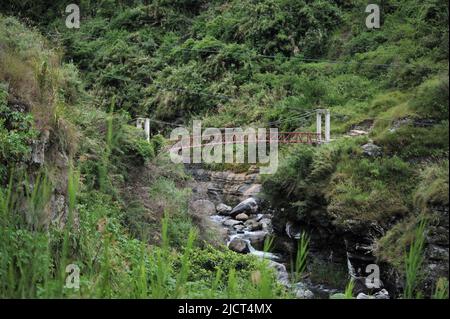 Mountain Province, Philippines: narrow metal bridge on top of a rocky stream on the way to Bomod-ok Falls. Stock Photo