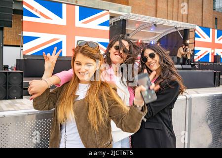 Three Young women celebrating the Queens Platinum Jubilee 2022 at Battersea Power Station in London, England, UK. Stock Photo