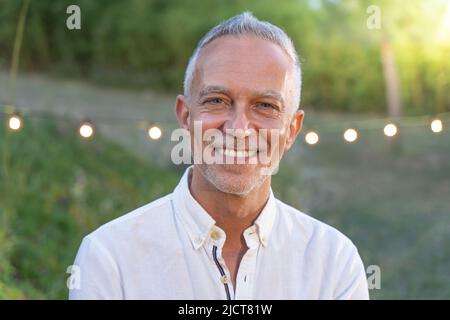 Middle-aged good looking man posing smiling in nature background. Stock Photo