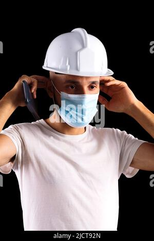 Young hispanic male construction worker putting on a mask Stock Photo