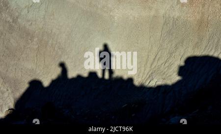 Shadow of a man against a background of dry cracked clay, cracks on the ground. Stock Photo