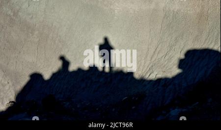 Shadow of a man against a background of dry cracked clay, cracks on the ground. Stock Photo