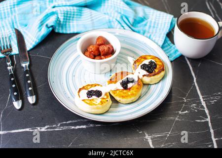 Sweet cheese pancakes on plate served strawberries. Syrniki, ricotta fritters, curd fritters. Stock Photo