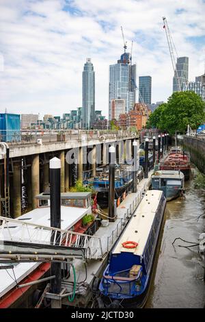 Residential boats moored in Nine Elms, Vauxhall, London with The Tower in the distance. Stock Photo