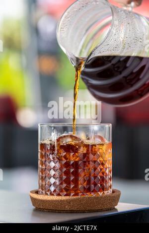 A cup of Iced Americano Coffee or Cold Brew coffee on a marble table in a coffee shop. Stock Photo