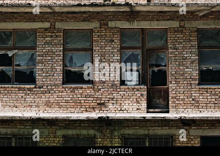 The wall of an old abandoned brick building with broken windows. Stock Photo