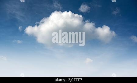 Blue sky and small fluffy single cloud illuminated by the day sun light. Nature background Stock Photo