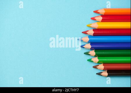 different colored pencils on a light blue background with space for any text Stock Photo