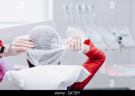 Young female patient sitting on a chair in the dental office. Preparing for a dental examination. Rear view. High quality photo Stock Photo