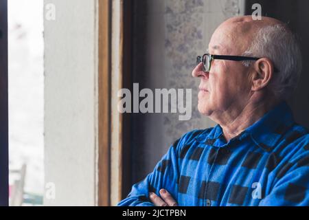 profile portrait of an elder Caucasian man looking out the window medium closeup indoor senior people concept. High quality photo Stock Photo
