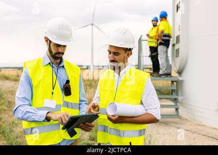 Two young maintenance engineers team working in wind turbine farm Stock Photo