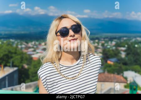 pretty Caucasian girl with sunglasses on the beautiful town background, medium closeup. High quality photo Stock Photo
