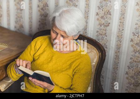 cute senior woman reading the Bible medium shot living room religion and spirituality concept. High quality photo Stock Photo
