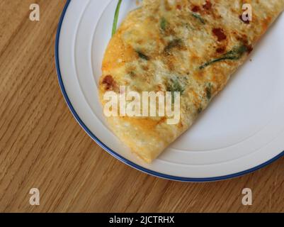 Top view of cooked omelette on white plate on wooden table Stock Photo