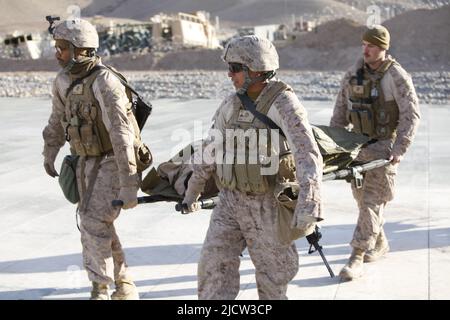 U.S. Marines alongside a U.S. Navy Hospital Corpsman, with 1st Battalion, 8th Marine Regiment (1/8), Regimental Combat Team 6, carry a wounded local A Stock Photo