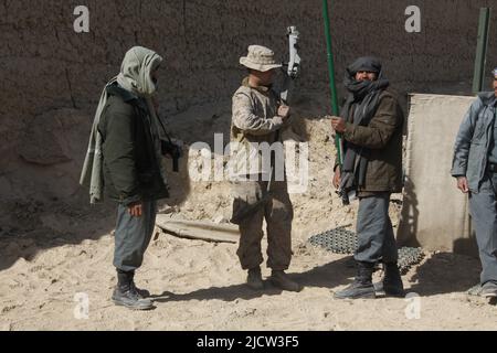 A U.S. Marine with the Police Advisory Team 2 (PAT 2) (left), 1st Battalion, 8th Marine Regiment, Regimental Combat Team 6, shows an Afghan Uniformed Stock Photo